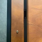 close-up of custom pivot front door with smart lock and brown wood panel